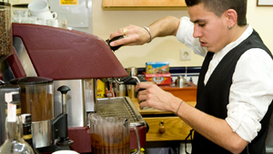 Imagen de un joven camarero preparando café.