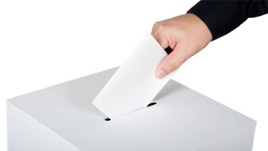 Imagen de una persona introduciendo su voto en una urna.